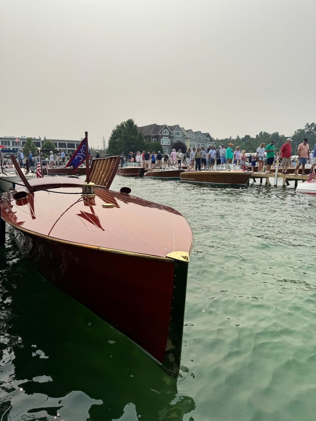 Classic mahogany wooden boats docked on Walloon Lake during the Walloon Woodies event with guests gathered along the pier.