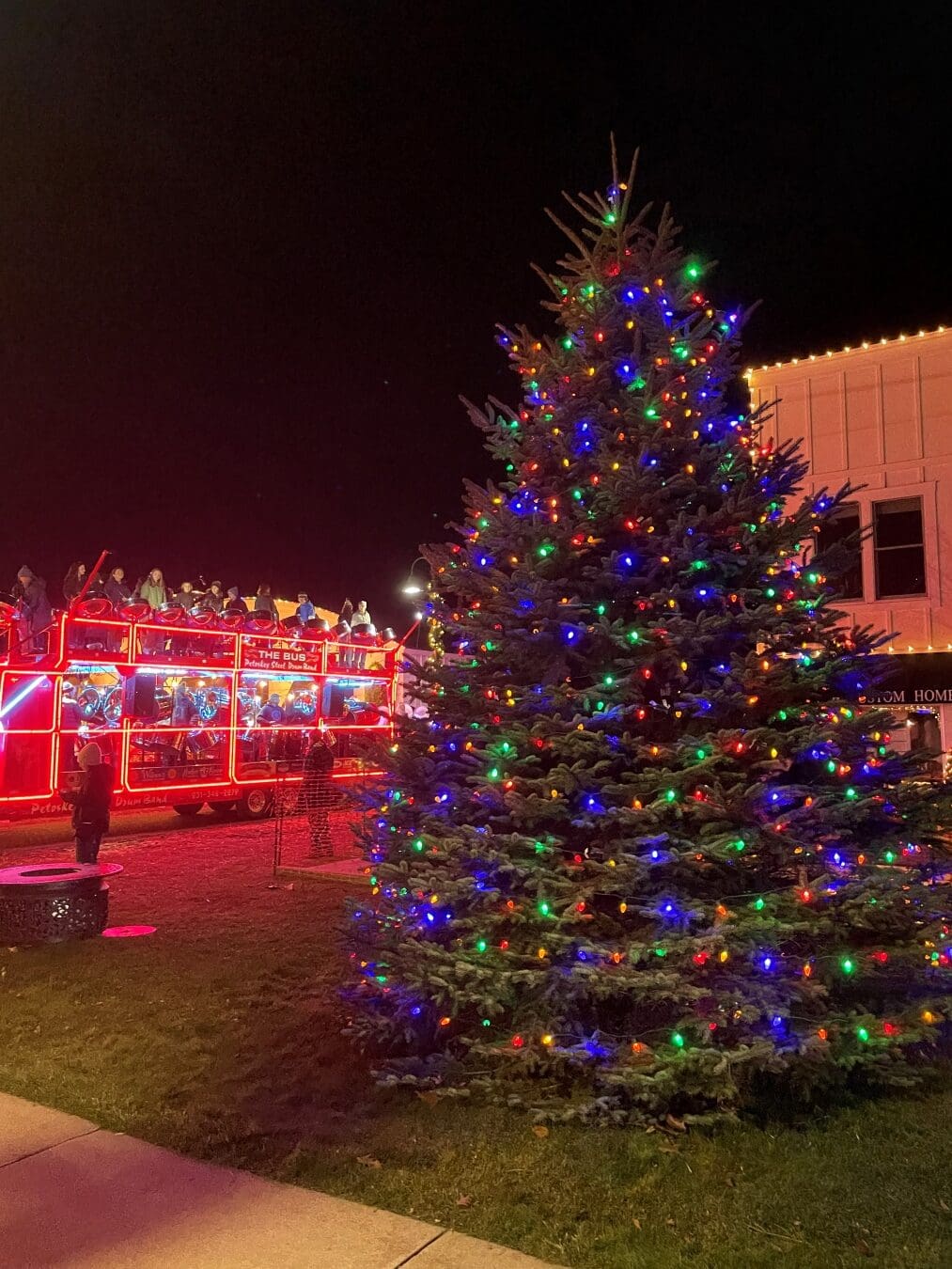 Large Christmas tree lit with colorful lights during the Lighting of the Village celebration.